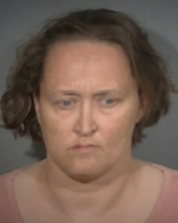 Woman with short curly hair and serious expression in a mugshot related to man accused of taking advantage and biological father plans.