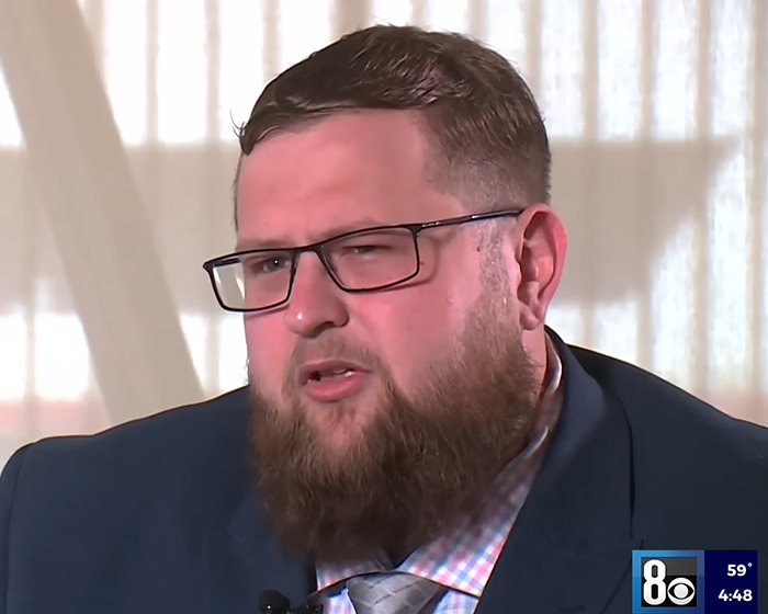 Man with glasses and beard in an interview setting discussing plans as potential biological father in family dispute.