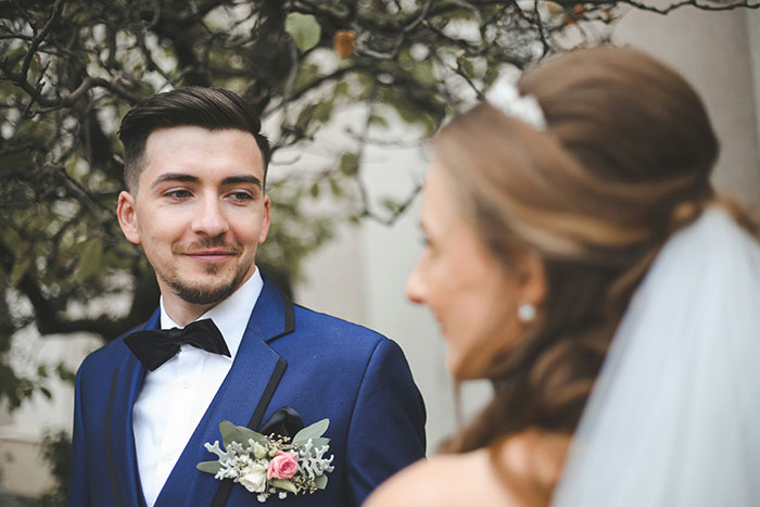 Groom in blue suit with boutonniere looking at bride outdoors, illustrating man urging gay brother to come out at wedding. Groom in blue suit with boutonniere looking at bride outdoors, illustrating man urging gay brother to come out at wedding.