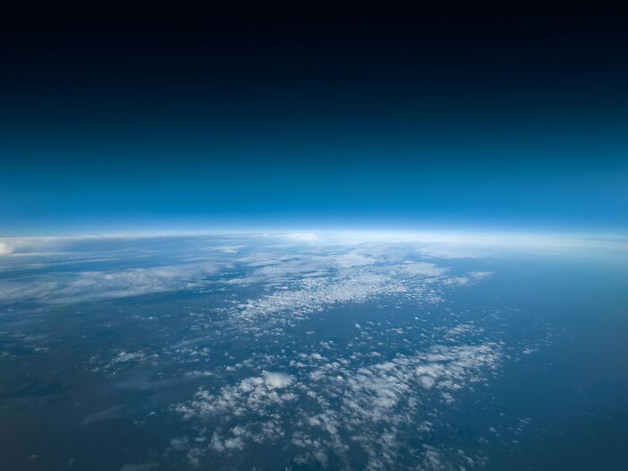View of Earth from high altitude with blue sky and scattered clouds, symbolizing bits of good news and hope.