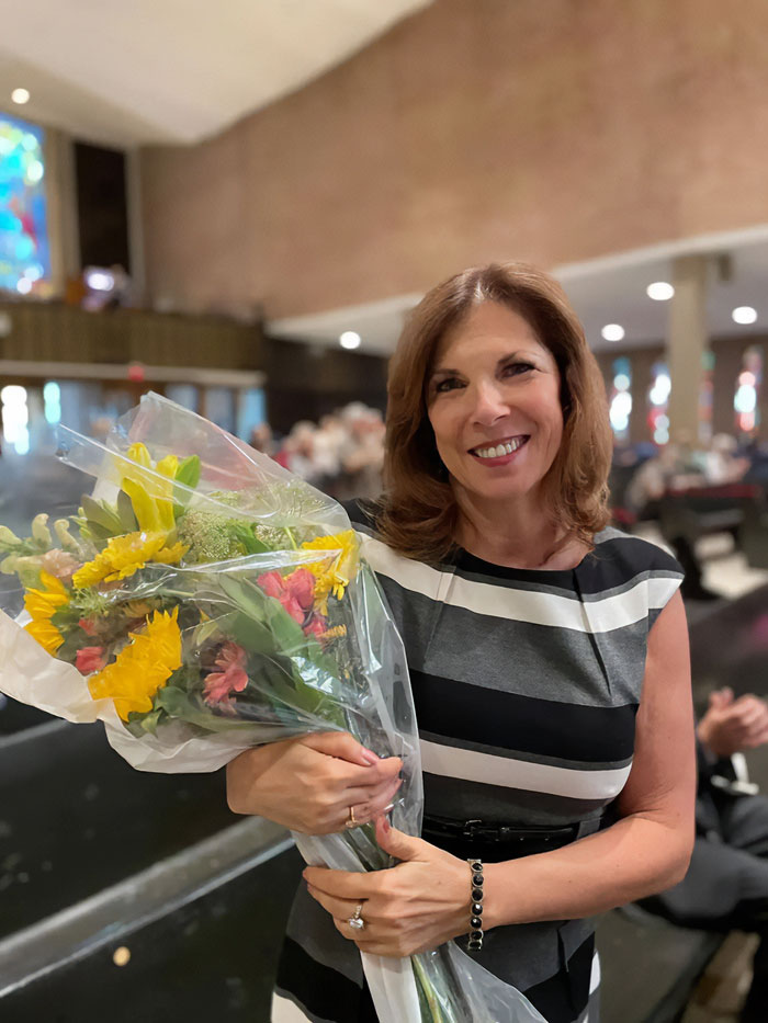 Woman smiling and holding a bouquet of flowers in a public setting related to Minneapolis school attacker mother debate.