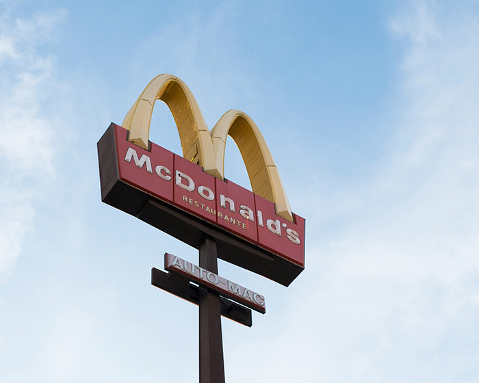 McDonald's sign against blue sky representing debate over two tier policy banning school kids.