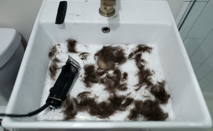 Sink filled with hair clippings and an electric razor, illustrating strange money-making hacks involving hair collection.