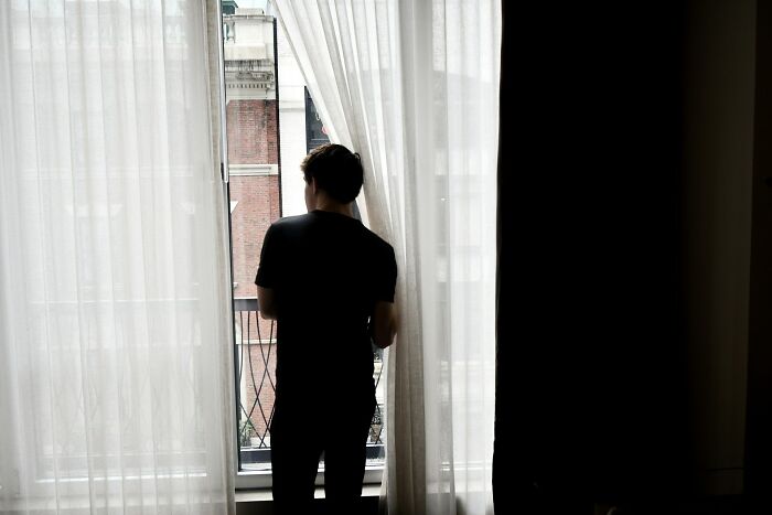 Person standing by a window with sheer curtains, evoking a creepy and disturbing scene police officers saw at a home.