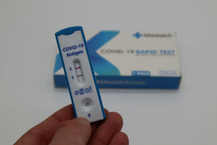 Hand holding a COVID-19 antigen rapid test showing a positive result, illustrating a common way to avoid babysitting.