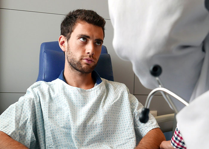 Young male patient in hospital gown listening to doctor, highlighting cases where doctors got it wrong and patient suffered.