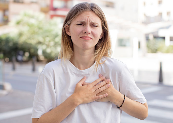 Young woman outdoors with chest pain, representing patients affected by doctors who got diagnosis wrong.