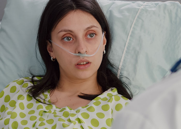 Young female patient on oxygen support in hospital bed, highlighting cases where doctors got diagnosis wrong.