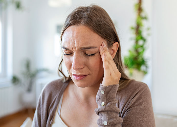 Young woman holding her head in pain, illustrating times doctors got diagnosis wrong and patient suffering.