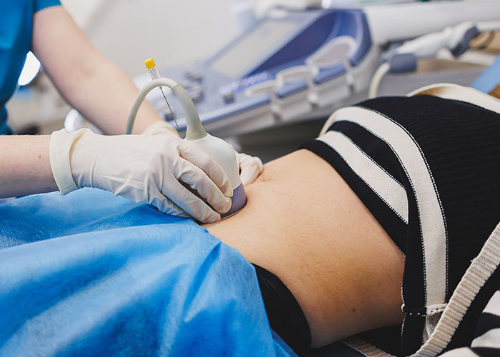 Medical professional wearing gloves performing ultrasound scan on a young patient's abdomen showing doctors getting it wrong.