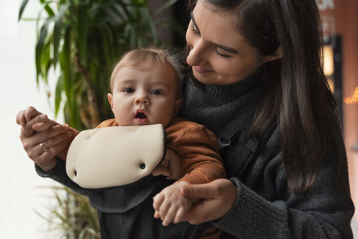 Woman holding baby in a carrier, depicting challenges hiring managers face with difficult people at work.