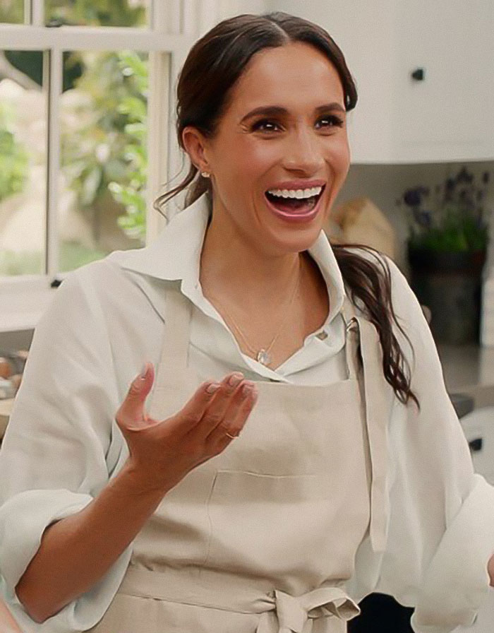 Meghan Markle smiling in a kitchen wearing an apron, related to cooking show and Pamela Anderson accusations. - 2