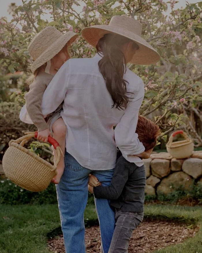 Meghan Markle outdoors wearing a hat, holding children in a garden setting, reflecting on Queen Elizabeth’s passing emotions. Meghan Markle outdoors wearing a hat, holding children in a garden setting, reflecting on Queen Elizabeth’s passing emotions.