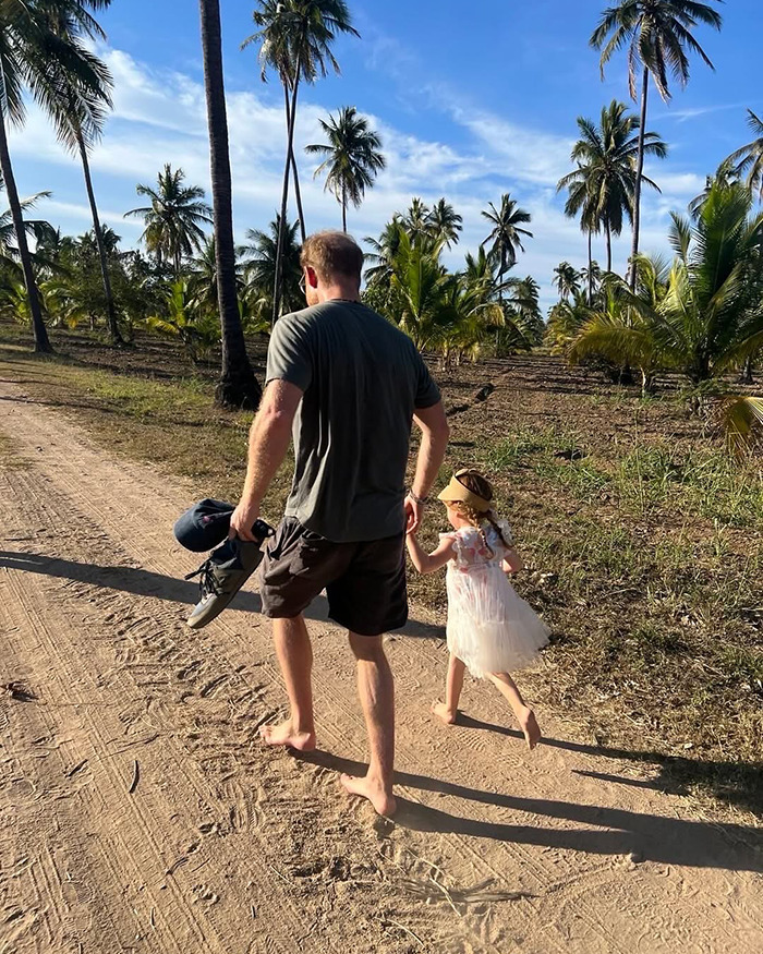Man and young girl walking barefoot on a dirt path lined with palm trees, reflecting on Meghan Markle emotional confession. Man and young girl walking barefoot on a dirt path lined with palm trees, reflecting on Meghan Markle emotional confession.