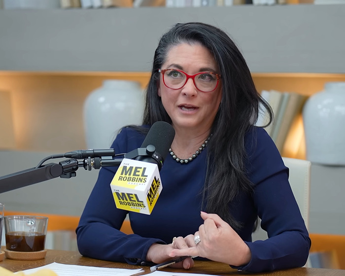 Woman with red glasses speaking into a microphone during a podcast about the push-ups challenge changing a woman&rsquo;s life.
