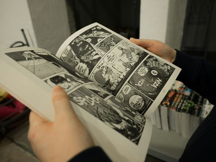 Person holding and reading a black and white comic book, illustrating a moment related to NSFW stories shared online.