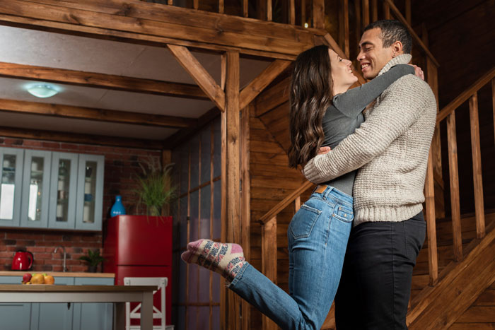 Couple embracing happily in cozy wooden home, highlighting woman saying no to future MIL&rsquo;s temporary stay before marriage.