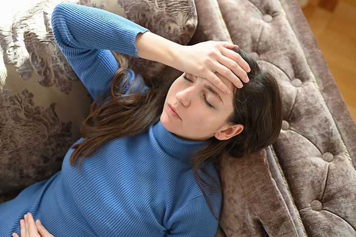 Young woman lying on a couch looking unwell, illustrating suspicion of poisoning in a family conflict scenario.