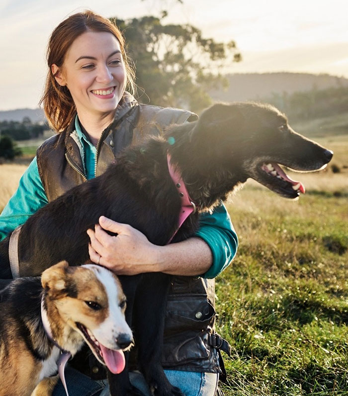 Woman on a dog meat farm holding two dogs outdoors, highlighting the owner of dog meat farm facing threats after going viral. - 8
