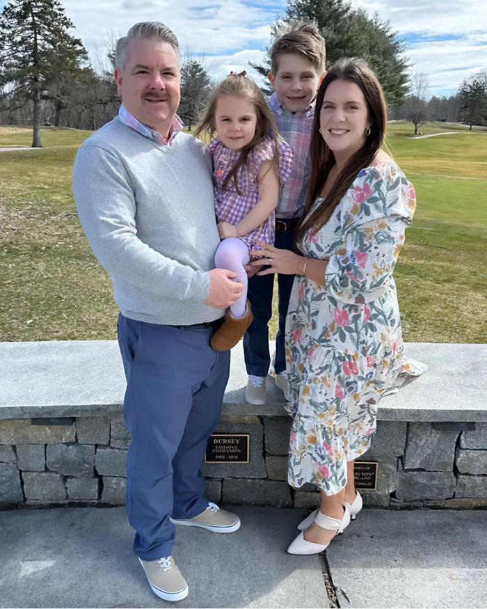 Family posing outdoors with parents and two children on a sunny day representing perfect family concept
