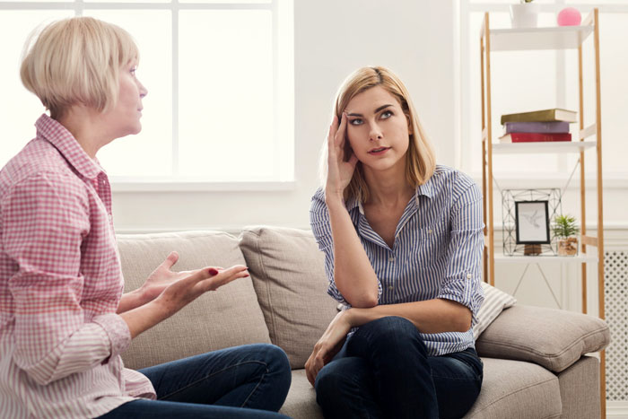 Bride looking uncomfortable while her mom insists on staying next door during wedding night in a tense living room conversation. Bride looking uncomfortable while her mom insists on staying next door during wedding night in a tense living room conversation.