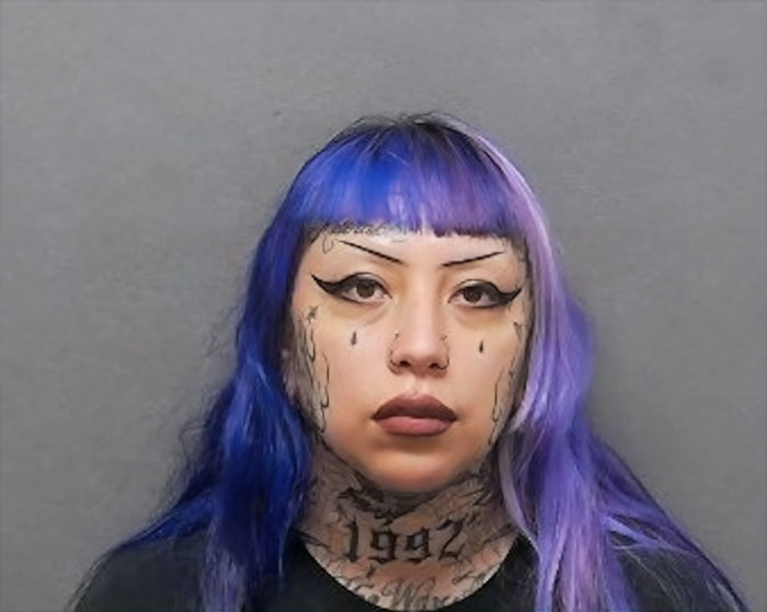 Woman with purple hair and face tattoos in a mugshot related to mom allegedly helping 13-year-old plan mass school shooting. - 1