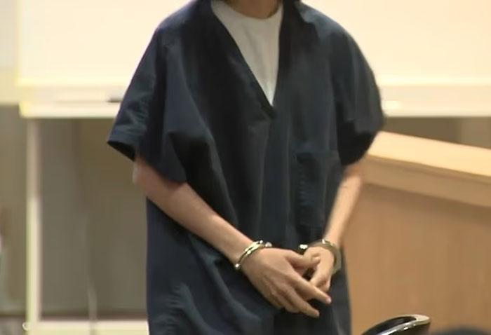 Woman in dark prison uniform wearing handcuffs, reportedly involved in helping son plan mass school shooting. - 4