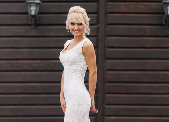 Woman wearing a white gown standing outdoors, illustrating bride's mom threatening to skip wedding over dress choice.