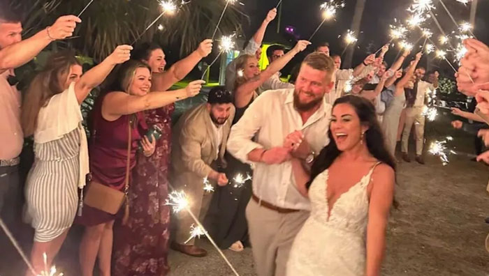 Bride and groom walking through a sparkler tunnel at night, one of the photos taken before disaster moments caught on camera.