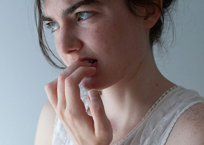 Young woman biting her nails looking thoughtful and anxious, illustrating common mind tricks that actually work. - 27