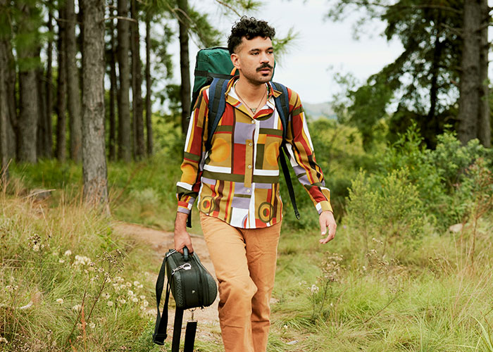 Man with backpack and guitar case walking through a forest path, illustrating creative mind tricks in nature. - 14
