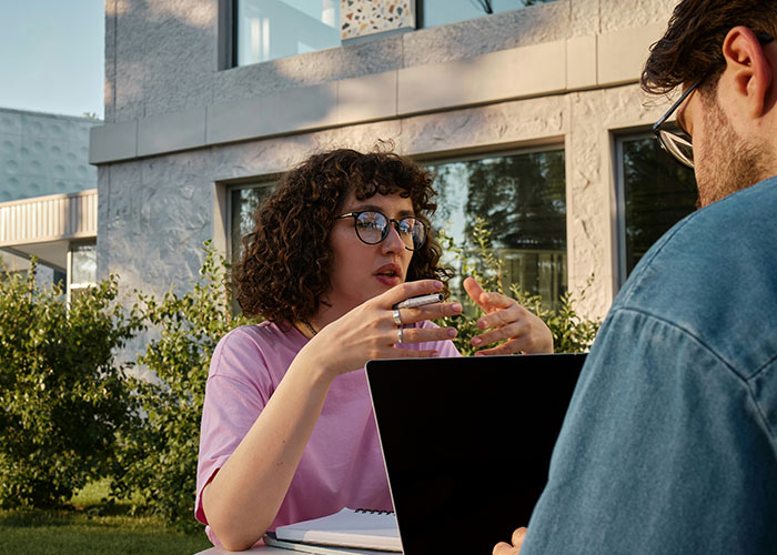 Two people outside discussing mind tricks with a laptop and notebook, demonstrating effective mind tricks in use. - 13