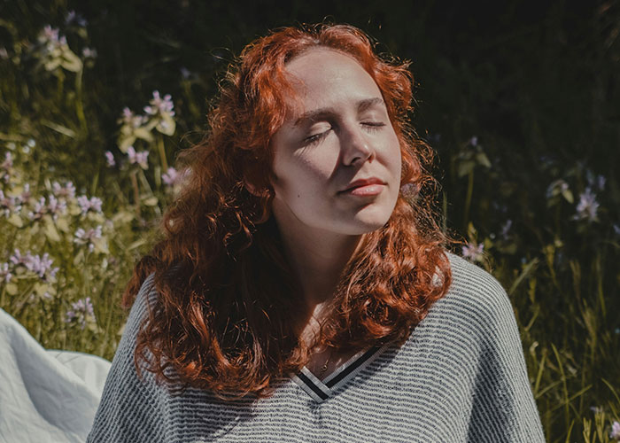 Young woman with red hair meditating outdoors, demonstrating mind tricks that actually work in a natural setting. - 35