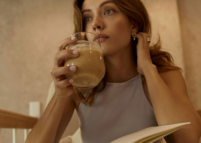 Young woman practicing mind tricks while drinking coffee and reading a book in a cozy indoor setting - 19