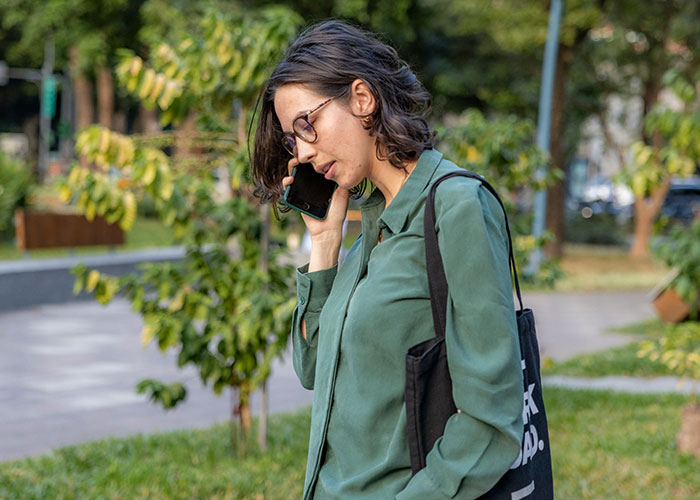 Woman in green shirt using a mind trick by talking on the phone outdoors, demonstrating mind tricks that work. - 31