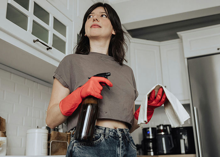 Woman wearing red gloves holding a spray bottle and cloth, demonstrating mind tricks that actually work for cleaning. - 34