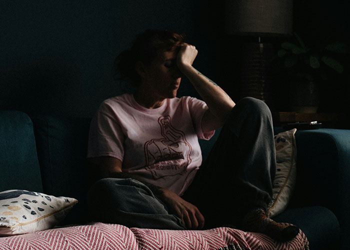 Person sitting in dim light with hand on forehead, illustrating mind tricks that actually work for mental stress relief. - 18