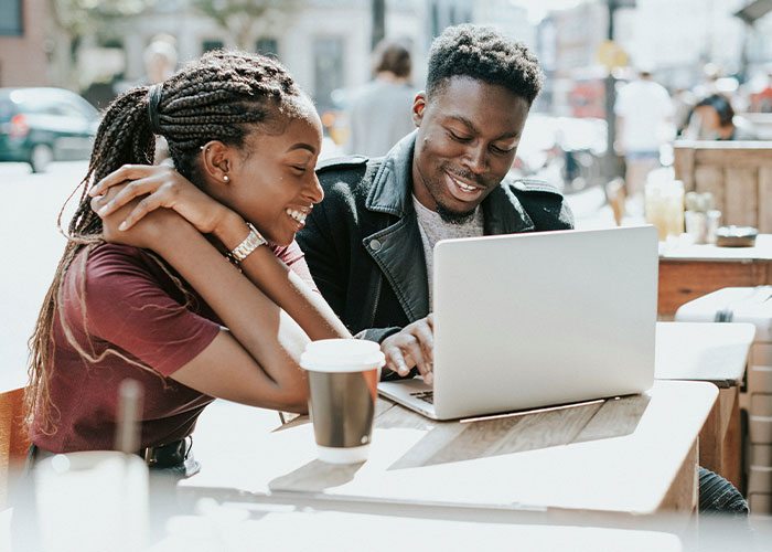 Two people smiling and discovering mind tricks that actually work while using a laptop at an outdoor café. - 25
