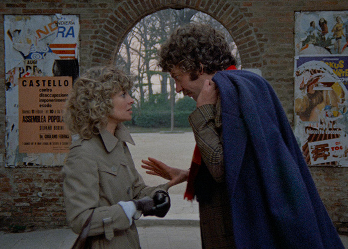 Two movie stars filming an intimate love-making scene outdoors beneath an old brick archway.