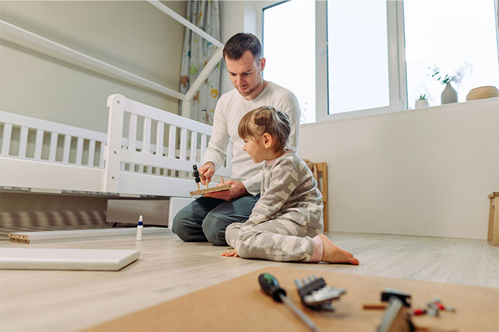 Dad building a toy with his girly daughter in a bright room, highlighting family bonding and parenting moments.