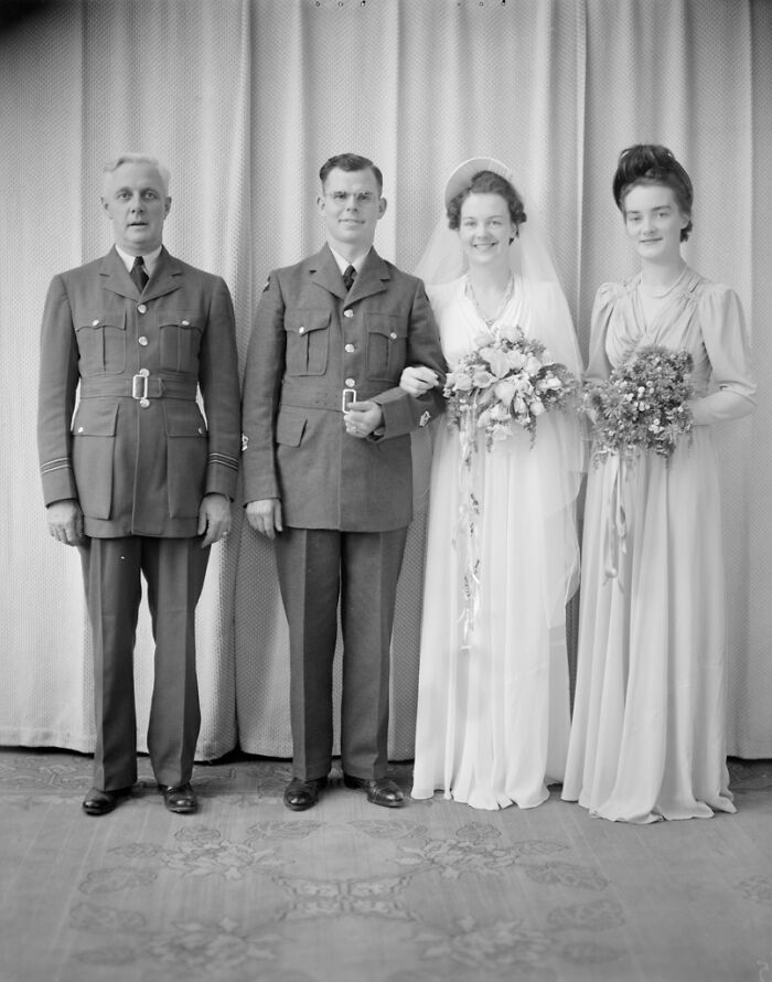1940s moving wedding photo with bride, groom in military uniform, and two attendants standing indoors against a curtain backdrop.