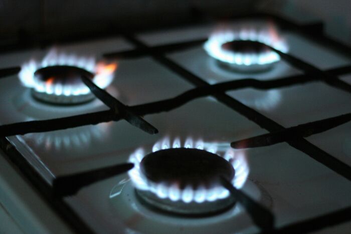 Close-up of gas stove burners lit with blue flames, illustrating unexpected and gross things witnessed in strangers’ homes.