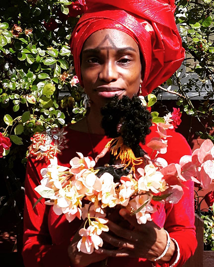 Woman in red headwrap holding floral arrangement outdoors, related to toddler passing due to vegan diet and ignored crucial signs.