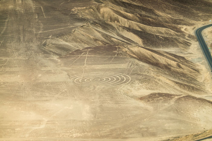 Aerial view of ancient geoglyphs etched into desert terrain, showcasing mysterious large-scale earth drawings.