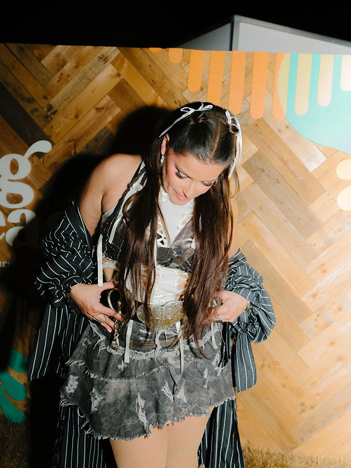 Nelly Furtado showing off natural curves onstage in a racy top and miniskirt with long hair and layered outfit.