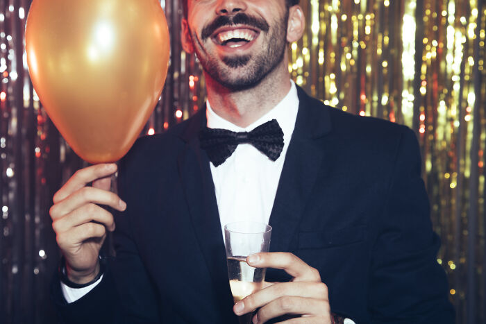 Man in tuxedo holding balloon and champagne glass at a party, illustrating the wealth gap perspective concept.