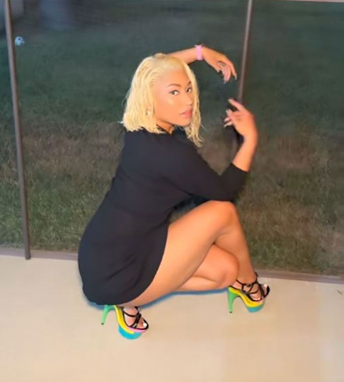 Influencer posing outdoors wearing colorful stilettos, linked to spine injury after attempting Nicki Minaj stiletto challenge.
