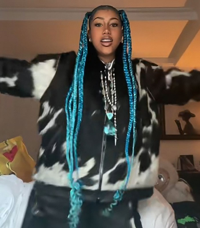 Young woman with long blue braids wearing a black and white jacket, representing a topic about North West corset controversy.
