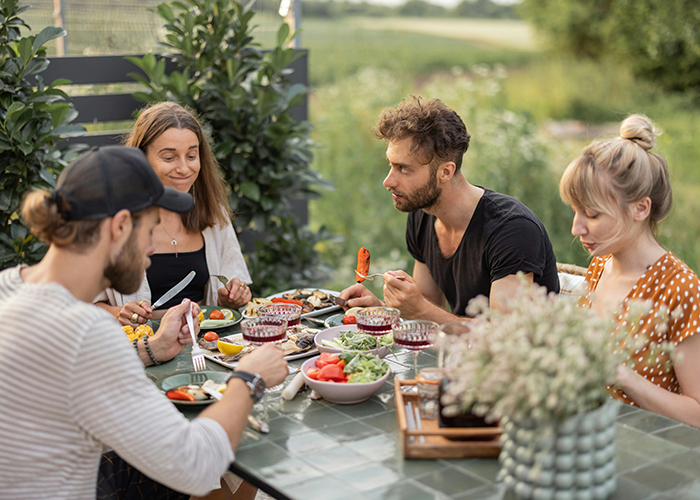 Group of tourists having a meal on a patio exterior, relating to neighbor refusing patio use and Airbnb discrimination claims.
