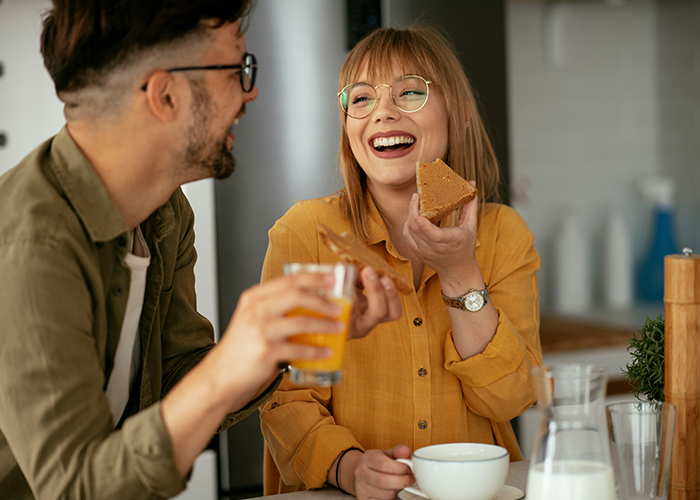 Couple enjoying breakfast together indoors, representing a neighbor refusing tourists patio use and Airbnb host dispute concept.